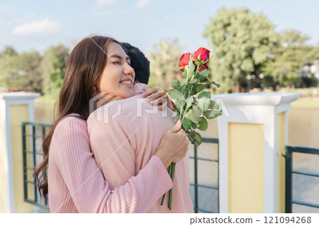 Valentine's day celebration romantic park setting couple embracing with roses joyful atmosphere outdoor view love concept 121094268