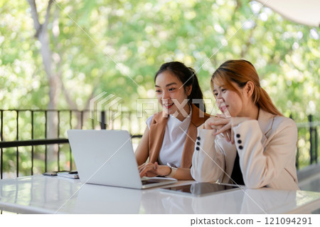 Empowering collaboration between two women outdoor greenery digital meeting vibrant nature close-up view teamwork in action 121094291