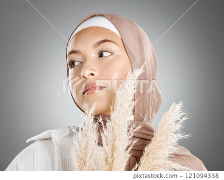 One beautiful young muslim woman wearing brown headscarf holding a pampas wheat plant isolated against grey studio background. Modest female arab wearing makeup with face covered in traditional hijab One beautiful young muslim woman wearing brown headscarf holding a pampas wheat plant isolated against grey studio background. Modest female arab wearing makeup with face covered in traditional hijab 121094338