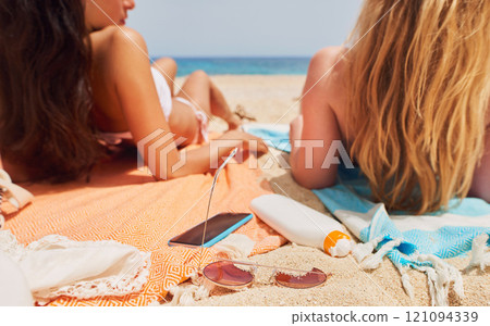 Girl friends, relax and back at beach with sunglasses, phone and sunscreen with talk, conversation or chat. Women together, smartphone and towel in summer sunshine, vacation and freedom with bikini Girl friends, relax and back at beach with sunglasses, phone and sunscreen with talk, conversation or chat. Women together, smartphone and towel in summer sunshine, vacation and freedom with bikini 121094339