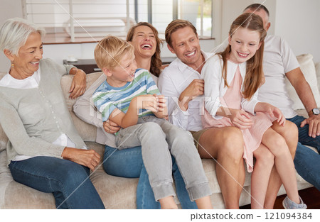 Portrait of a happy family laughing and sitting on the couch in the living room. Little girl and boy bonding with parents and grandparents in the living room. Grandparents visiting the grandchildren 121094384