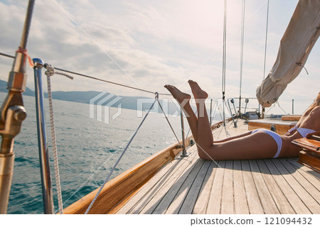 Woman, legs and sun tanning on yacht for summer break, holiday and travel adventure in Maldives. Body, bikini and girl on luxury boat deck, sea and ocean for nature cruise, sailing or water vacation 121094432