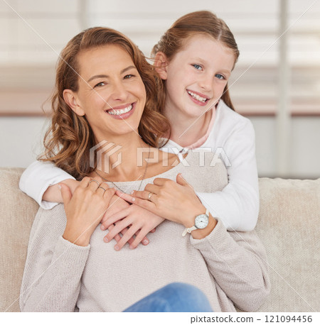 Portrait of a single mother and her daughter. Adorable girl bonding with her single parent and hugging in the living room at home. Smiling woman and her affectionate kid enjoying free weekend time 121094456