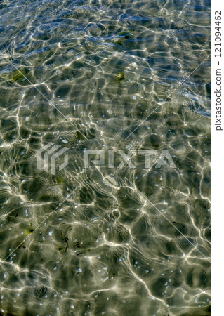 A closeup of the shallow seabed with shells at the bottom, crystal clear water on the surface of a sea. Clear sparkling water reflects the sunlight in the ocean. Full view of clear lake water ground A closeup of the shallow seabed with shells at the bottom, crystal clear water on the surface of a sea. Clear sparkling water reflects the sunlight in the ocean. Full view of clear lake water ground 121094462