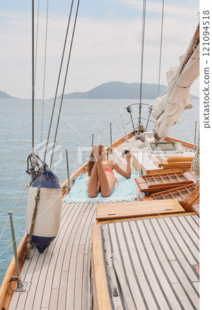Travel, yacht and women with phone on boat relax for cruise on holiday, vacation and adventure at sea. Luxury sailing, sunbathing and female person on smartphone for social media, memories and online 121094518