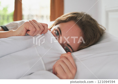 Portrait, woman and peeking in bed cover to wake up, relax and peace in home bedroom. Hiding face, morning and person in duvet for comfort, healthy rest and eyes of shy girl on pillow in Switzerland 121094594