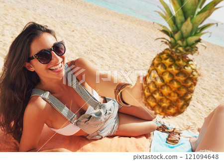 Pineapple, relax and portrait of a woman on the beach to relax on holiday or vacation during summer. Travel, smile and a happy young person with fruit on the sand by the ocean or sand for tourism Pineapple, relax and portrait of a woman on the beach to relax on holiday or vacation during summer. Travel, smile and a happy young person with fruit on the sand by the ocean or sand for tourism 121094648