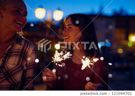 Happy woman, friends and night with sparklers for party, celebration or new year together in city. Young, female person or women with fireworks in late evening for cheerful holiday or festive season 121094702