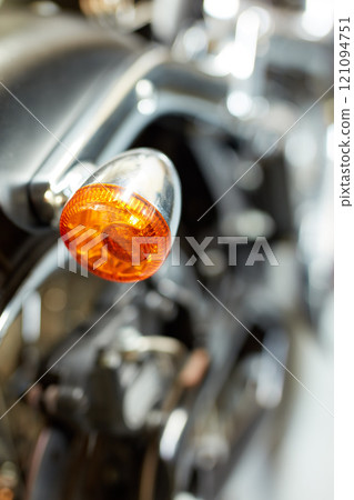 Closeup rear view of a taillight on a motorbike. Orange turning light on a blurred black vintage motorcycle. One modern chrome transportation vehicle. Maintenance on a shiny classic retro custom bike Closeup rear view of a taillight on a motorbike. Orange turning light on a blurred black vintage motorcycle. One modern chrome transportation vehicle. Maintenance on a shiny classic retro custom bike 121094751