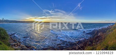 Vivid sunset over a calm ocean horizon, blending vibrant orange and blue hues, evoking serenity 121094819
