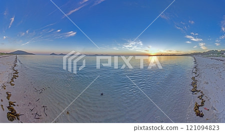 Vivid sunset over a calm ocean horizon, blending vibrant orange and blue hues, evoking serenity 121094823