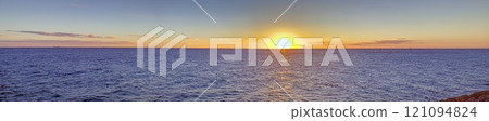 Vivid sunset over a calm ocean horizon, blending vibrant orange and blue hues, evoking serenity Vivid sunset over a calm ocean horizon, blending vibrant orange and blue hues, evoking serenity 121094824