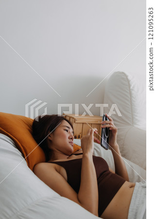 Happy woman using mobile phone relaxed on sofa in the living room. 121095263