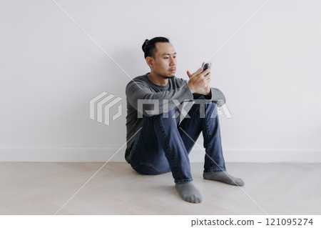Creative freelance man sitting on the floor looking at the phone. Creative freelance man sitting on the floor looking at the phone. 121095274