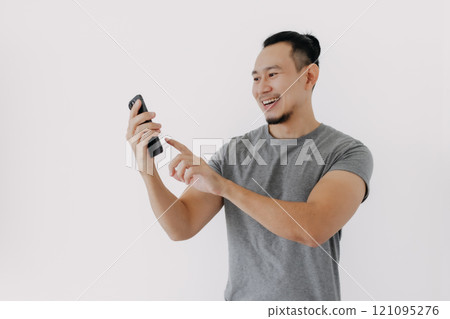 Happy smile face of man in grey t-shirt using smartphone app on white. Happy smile face of man in grey t-shirt using smartphone app on white. 121095276
