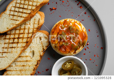 Portion of baked brie with jalapeno and toast 121095328