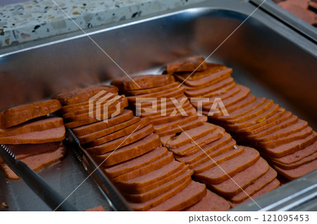 Block of Spam luncheon meat cut into slices on a cutting board. Knife is in the background. Block of Spam luncheon meat cut into slices on a cutting board. Knife is in the background. 121095453