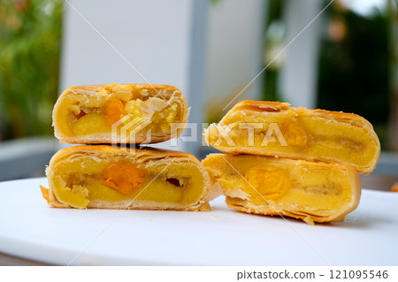 High angle view of whole and two halves chinese pastry or moon cake filled with sweet mung bean paste and salted egg yolk. 121095546