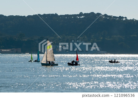 small boats with colorful sails, sailboats on the river at sunset small boats with colorful sails, sailboats on the river at sunset 121096536