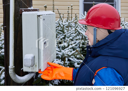 Power company technician inspects outdoor household electrical equipment in rural community. 121096927
