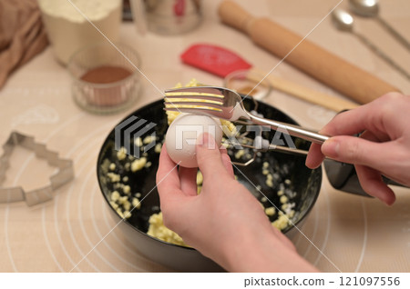 Christmas homemade baking, ingredients for baking gingerbread, woman fork breaks an egg in black bowl 121097556