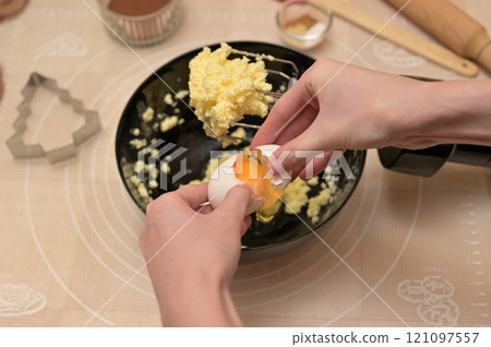 Christmas homemade baking, ingredients for baking gingerbread, woman hands breaks an egg in black bowl 121097557