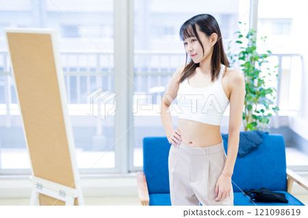 年輕女性在全身鏡前選擇衣服和內衣，選擇運動胸罩和內衣 121098619