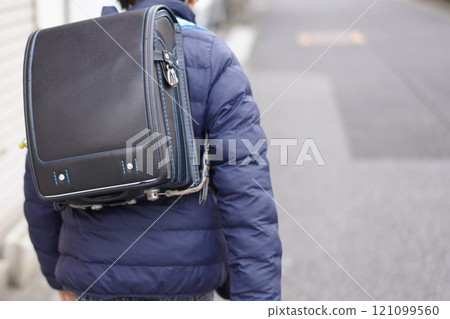 Back view of a boy walking with a school bag on his back in winter Back view of a boy walking with a school bag on his back in winter 121099560