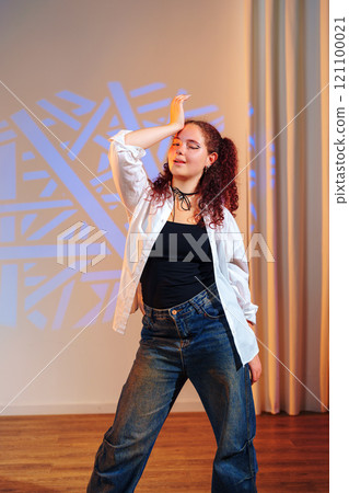 A young woman with long red hair poses in a dance studio A young woman with long red hair poses in a dance studio 121100021