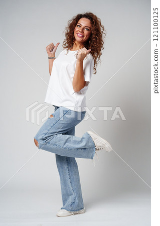 Young woman joyfully celebrates in casual attire against a neutral background 121100125