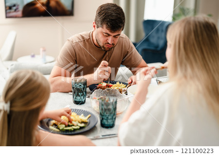 A family enjoys a meal together at a dining table 121100223