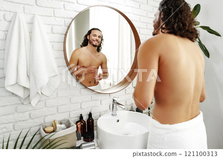 A man prepares for the day in a bright bathroom 121100313