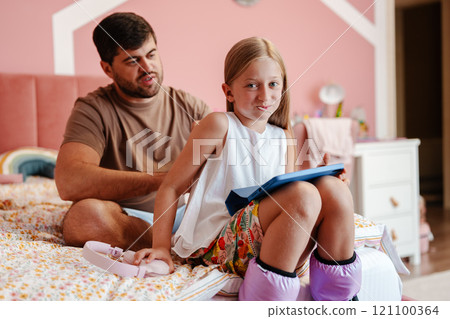 Father and daughter share a playful moment together in cozy bedroom 121100364