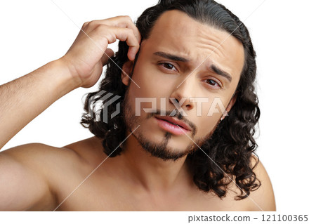 Young man with curly hair thoughtfully posing against a plain background 121100365