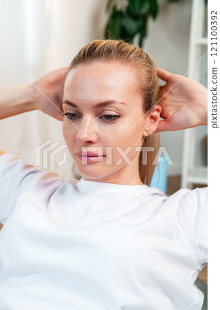 Woman performing a stretching exercise in a bright indoor 121100392