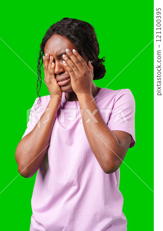 Woman expressing frustration while standing against a bright green background 121100395