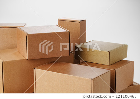 Stacked brown cardboard boxes in various sizes arranged on a white background Stacked brown cardboard boxes in various sizes arranged on a white background 121100463