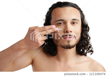 A young man demonstrates skincare routine with moisturizer on his face A young man demonstrates skincare routine with moisturizer on his face 121100474