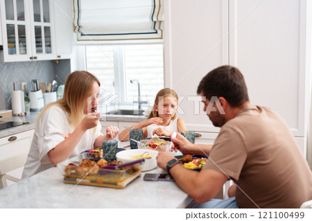A family is eating dinner in their kitchen A family is eating dinner in their kitchen 121100499