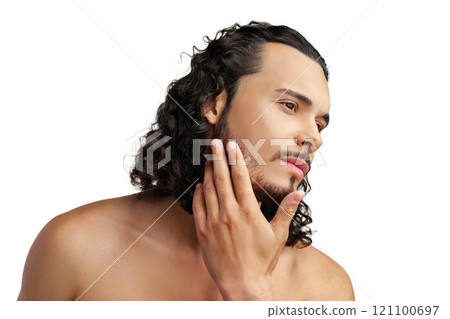 Young man with curly hair thoughtfully posing against a plain background 121100697