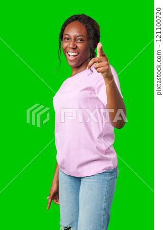 Young woman in a pink shirt playfully pointing fingers at the camera against a bright green background Young woman in a pink shirt playfully pointing fingers at the camera against a bright green background 121100720