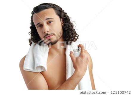 A young man with curly hair applying fragrance after a shower while smiling at the camera 121100742