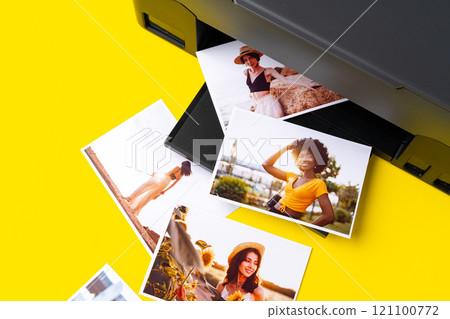 Printer printing colorful photos of people close up, yellow background Printer printing colorful photos of people close up, yellow background 121100772