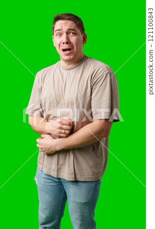 Man expressing fear while standing against a bright green background Man expressing fear while standing against a bright green background 121100843