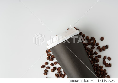 A paper coffee cup surrounded by freshly roasted coffee beans on a clean white background A paper coffee cup surrounded by freshly roasted coffee beans on a clean white background 121100920
