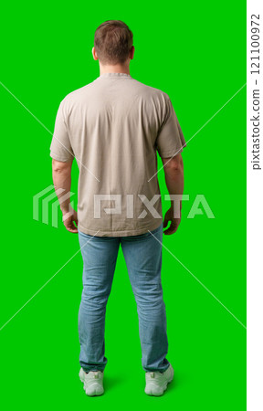 A man in casual clothing stands with his back to the camera against a bright green background A man in casual clothing stands with his back to the camera against a bright green background 121100972