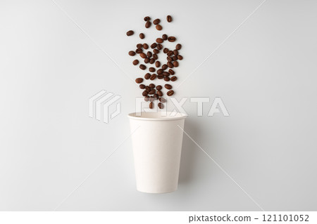 A paper coffee cup surrounded by freshly roasted coffee beans on a clean white background A paper coffee cup surrounded by freshly roasted coffee beans on a clean white background 121101052