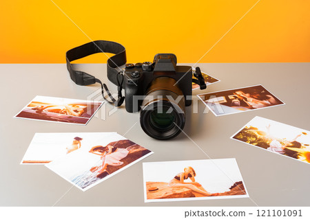 Photo camera with colorful printer photos on gray desk 121101091