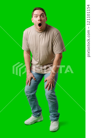Young man in casual clothing stands with open arms against a vibrant green background Young man in casual clothing stands with open arms against a vibrant green background 121101154