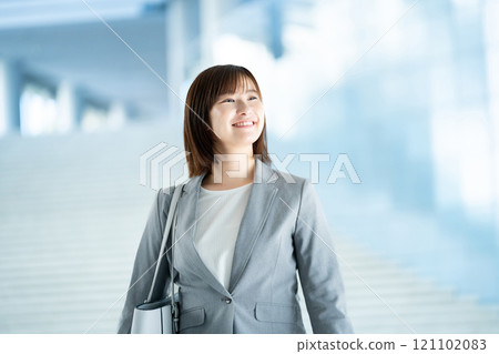 A woman in a suit going to work, an office lady walking through a bright lobby, a working office lady 121102083